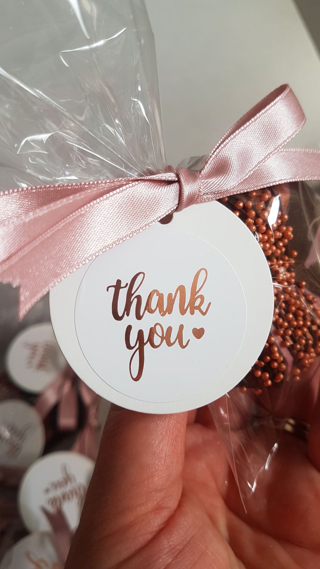 Chocolate geo heart, packaged with pink ribbon and 'thank you' tag held by a hand in a cellophane bag