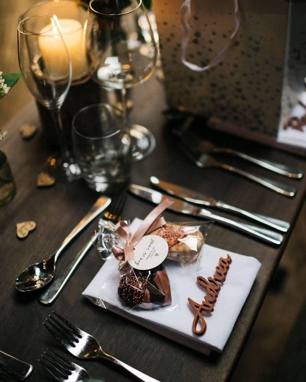 Wedding table, set with 2 weddings favours, wrapped in cellophane and tied with pink ribbon, with a circular disk card with a message on.