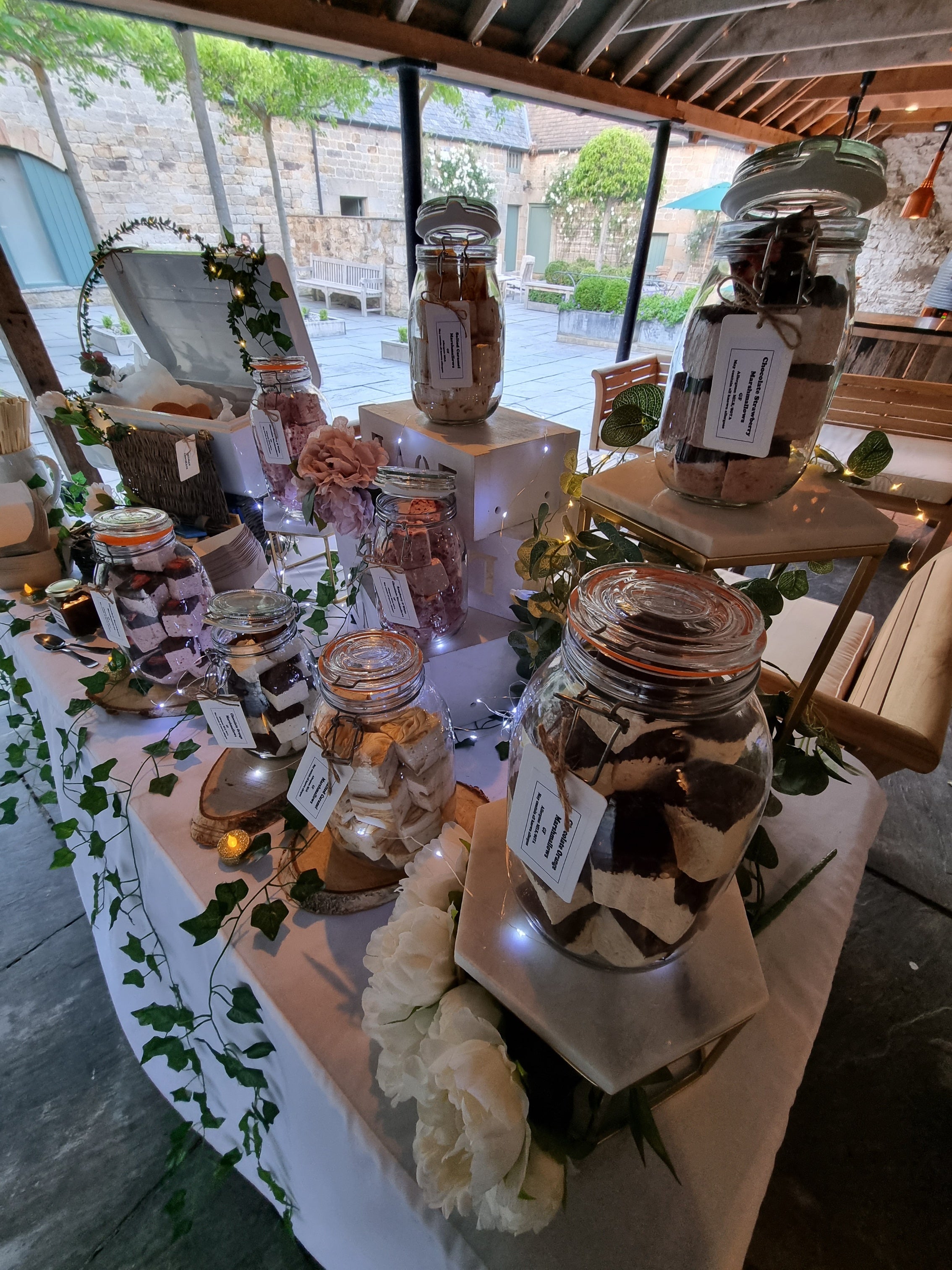 Table with jars filled with marshmallows and decorative items outdoors at healey barn wedding venue northumberland smores station
