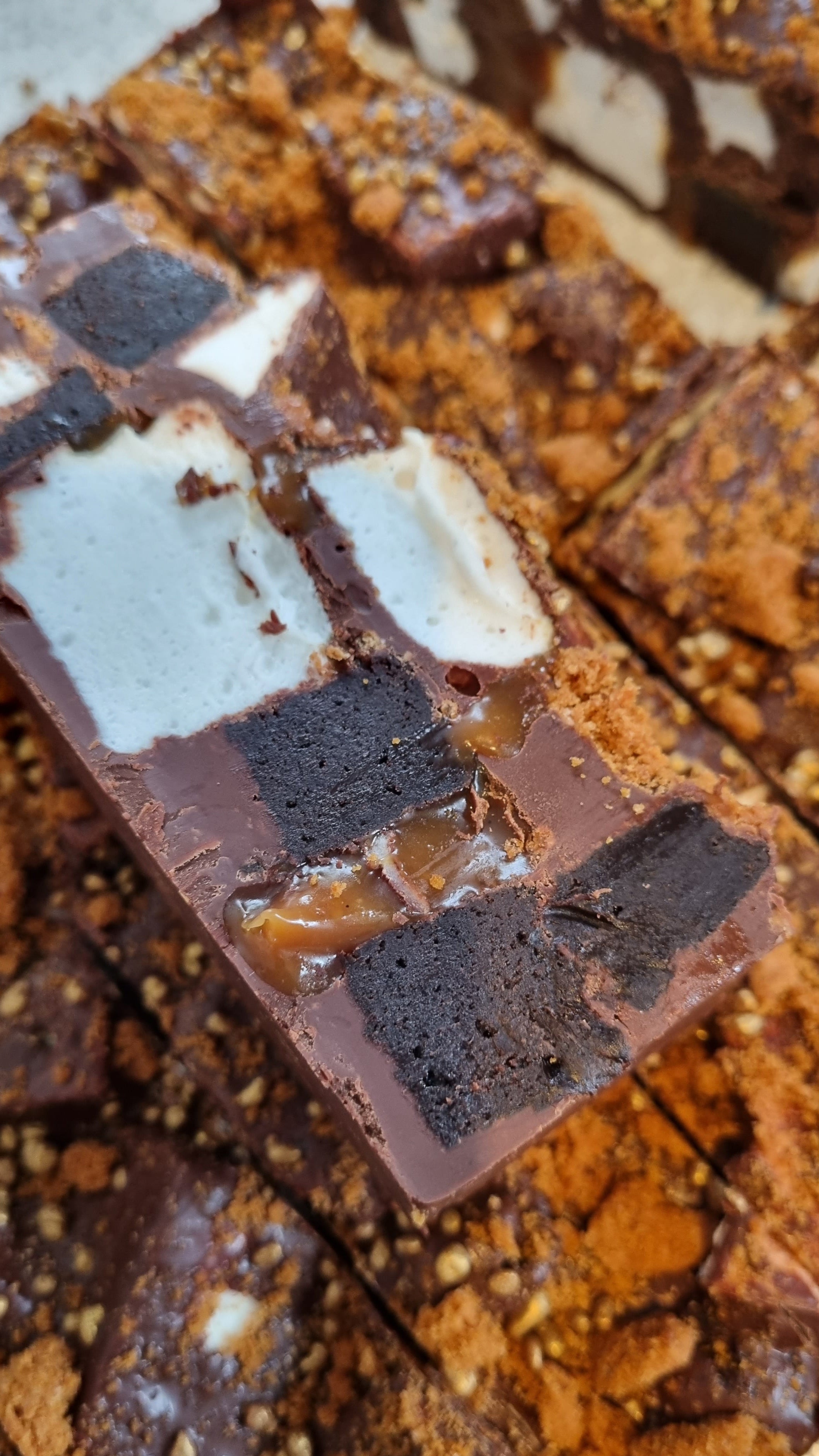 Close-up of a chocolate rocky road dessert with marshmallows and brownies on a textured surface