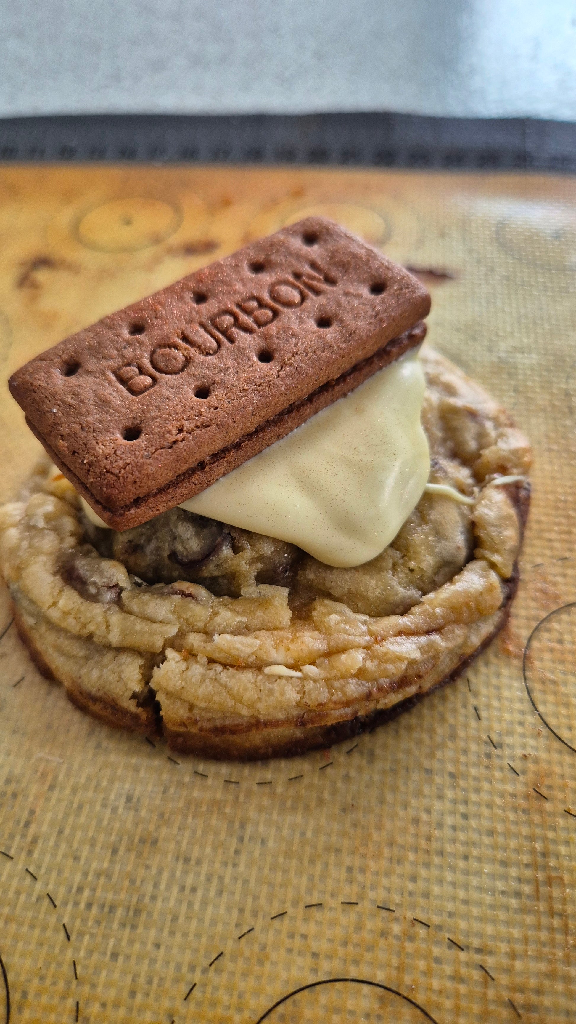Chocolate chip cookie topped with white chocolate & q bourbon biscuit on a wooden board