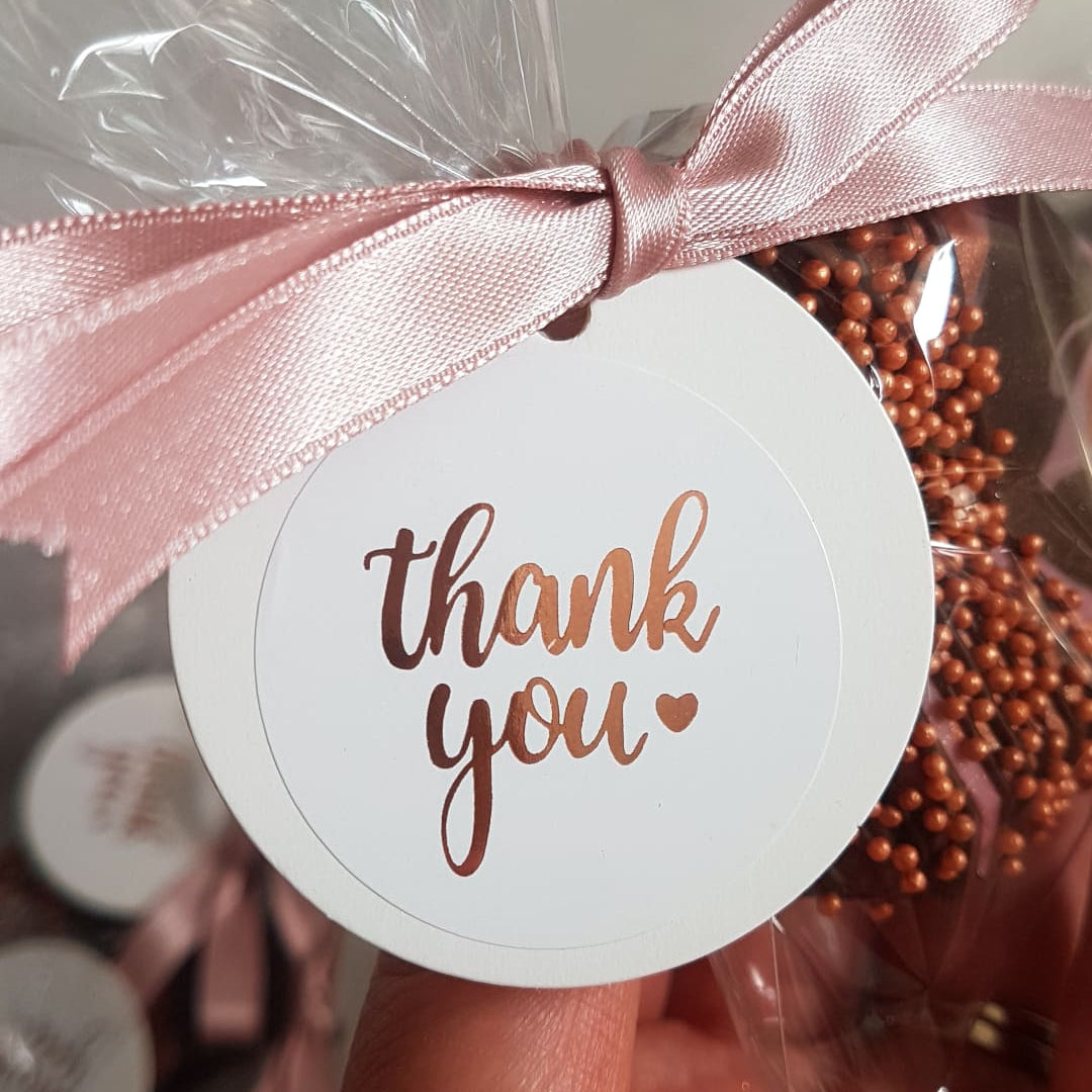 Corporate Gift geo heart with pink ribbon and 'thank you' tag, surrounded by small round objects.