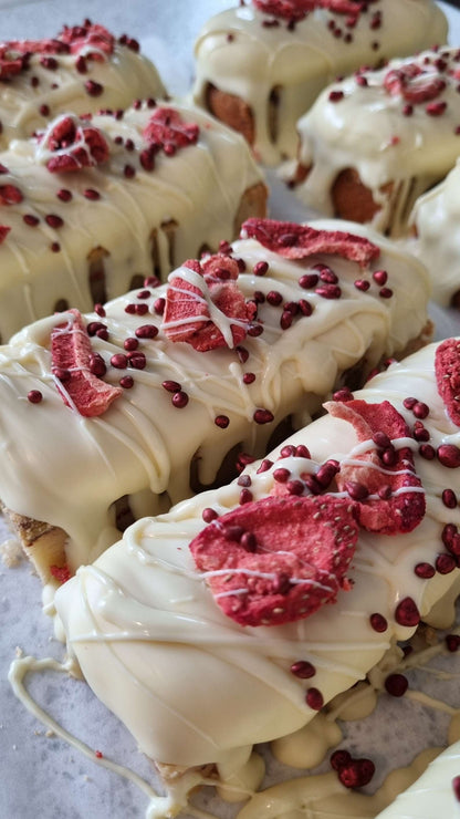 multiple blondies topped with white chocolate and red raspberry pieces on a light background
