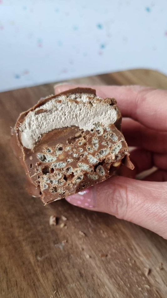 Handmade Chocolate Bar - Double Decker held by hand. layered chocolate crispies with a nougat and caramel top then all dipped in chocolate.